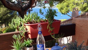 A wooden table with a bottle of water, a teapot, bowls, and a plate of fruit. - T2 vue mer 180° Avec balcon, Air-conditioned, direct access to the sea, Parking, Piscine (Saint-Cyr-sur-Mer)