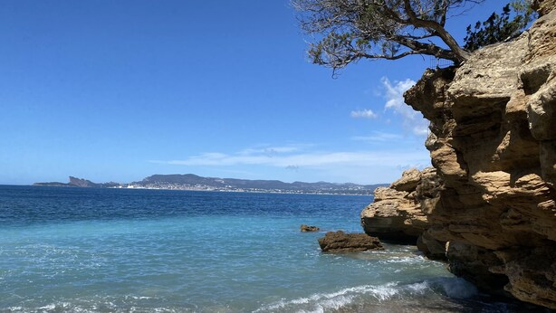 A rocky shoreline with clear blue water, pebbles, and a distant view of a town and mountains. - T2 vue mer 180° Avec balcon, Air-conditioned, direct access to the sea, Parking, Piscine (Saint-Cyr-sur-Mer)