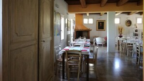 A dining area with wooden tables and chairs, a fireplace, and a painting on the wall. - Agriturismo Morattina (Brisighella)