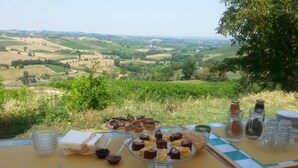 A table set outdoors with desserts and drinks, overlooking a scenic countryside view. - Agriturismo Morattina (Brisighella)