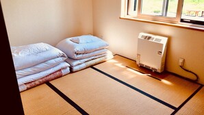 Quarto com tatames, aquecedor e roupa de cama bem organizada.