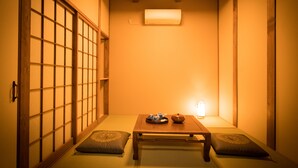 Une pièce de style japonais traditionnel, avec un sol recouvert de tatamis, une petite table en bois et un service à thé, ainsi que des portes coulissantes.