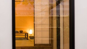Une photographie encadrée représentant l’intérieur d’une pièce avec un lit, une table de chevet et une lampe.