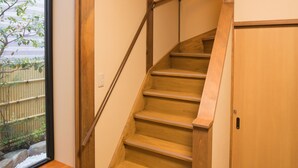 Un escalier en bois, muni d’une rampe, qui mène à une porte.