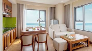 A modern hotel room with a dining area, a sofa, and a view of the sea.