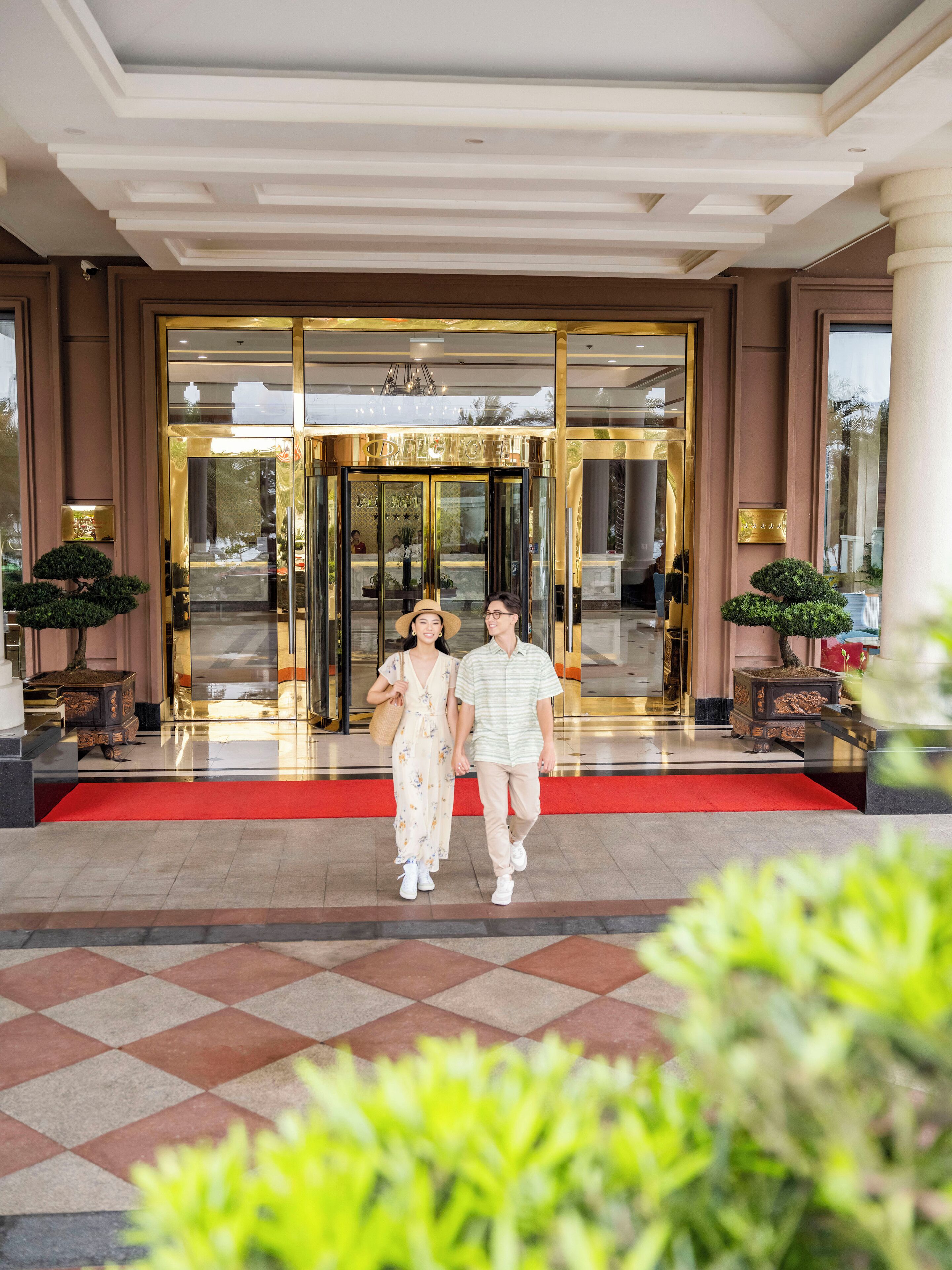 L’entrée d’un hôtel, avec un tapis rouge, une porte en verre et une enseigne au-dessus de la porte.