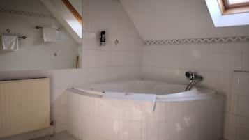 A bathroom with a freestanding bathtub, a radiator, a towel rack, and a skylight.