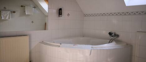 A bathroom with a freestanding bathtub, a radiator, a towel rack, and a skylight.