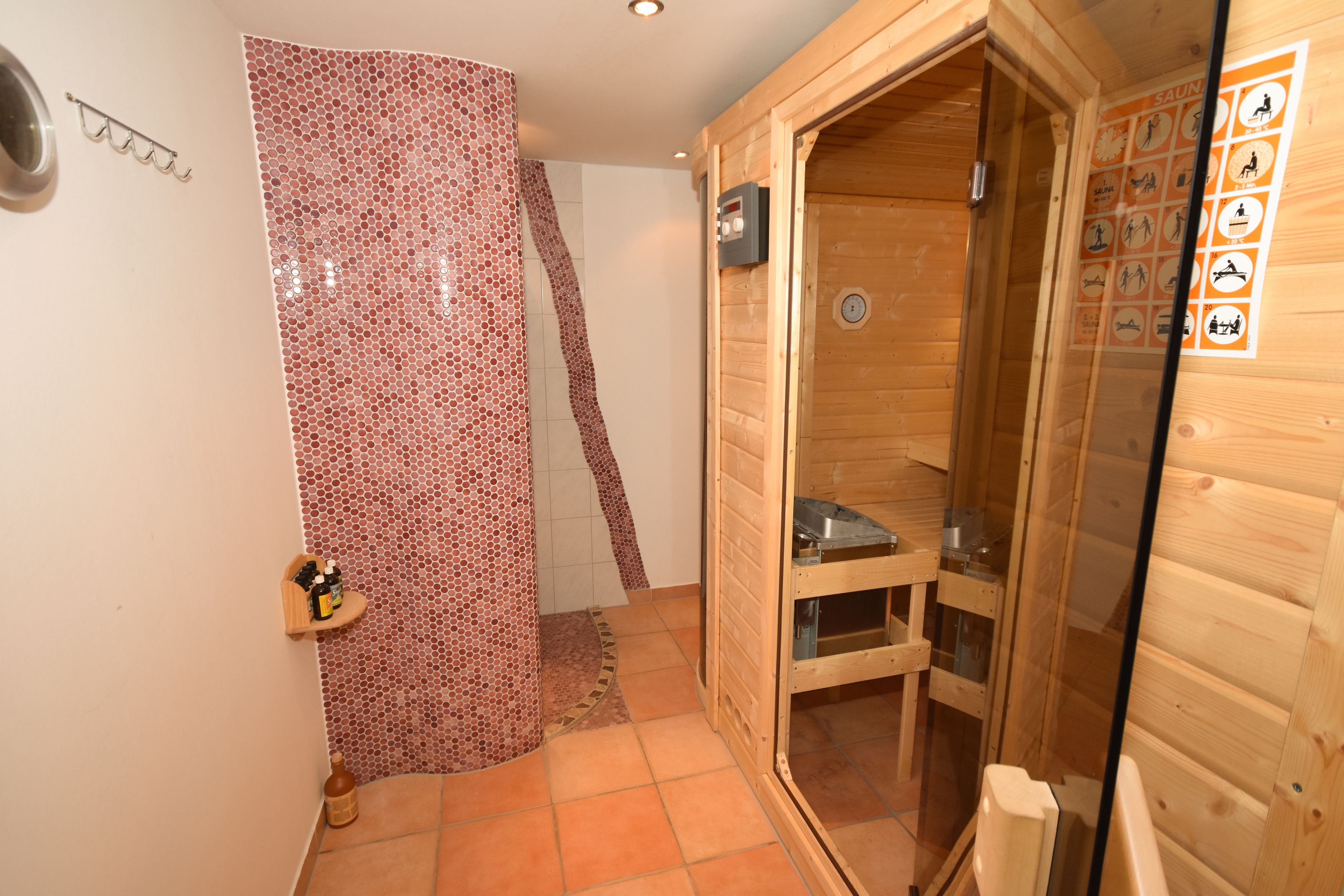 A sauna room with wooden walls, a tiled floor, and a glass door.