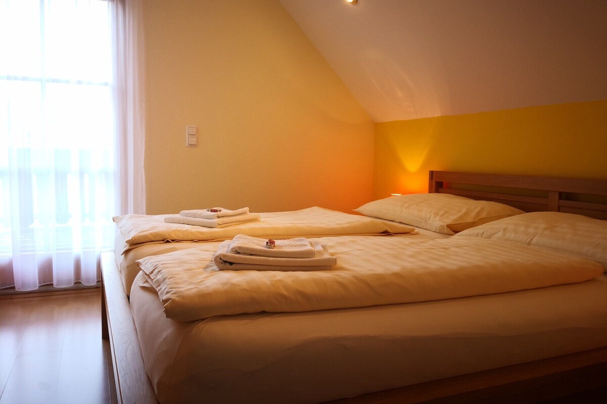 A room with two beds, each with neatly folded towels and pillows.