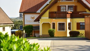 A yellow building with a red-tiled roof, a balcony, and a sign for 'Sonnenberg Hotel & Spa'. - Golf & Therme Sonnenpension Hotel Garni (Burgauberg-Neudauberg)
