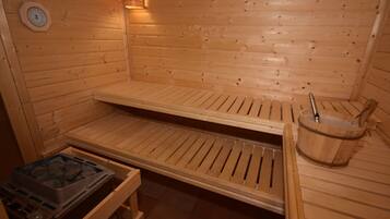 Una sauna de madera con bancos, un balde de madera y un calentador de sauna.