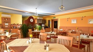 A restaurant with wooden tables and chairs, a clock on the wall, and potted plants. - Golf & Therme Sonnenpension Hotel Garni (Burgauberg-Neudauberg)