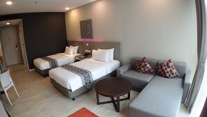 Habitació d'hotel amb dos llits, un sofà, una taula petita i una cadira.