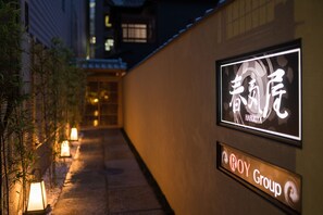 A pathway with illuminated signs and plants. - Harukiya (Osaka)