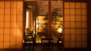 Una habitación japonesa tradicional con suelo de tatami, una mesa baja y dos sillas.