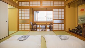 Una habitación tradicional japonesa con suelo de tatami, una mesa baja con sillas y una puerta corrediza con paneles shoji.