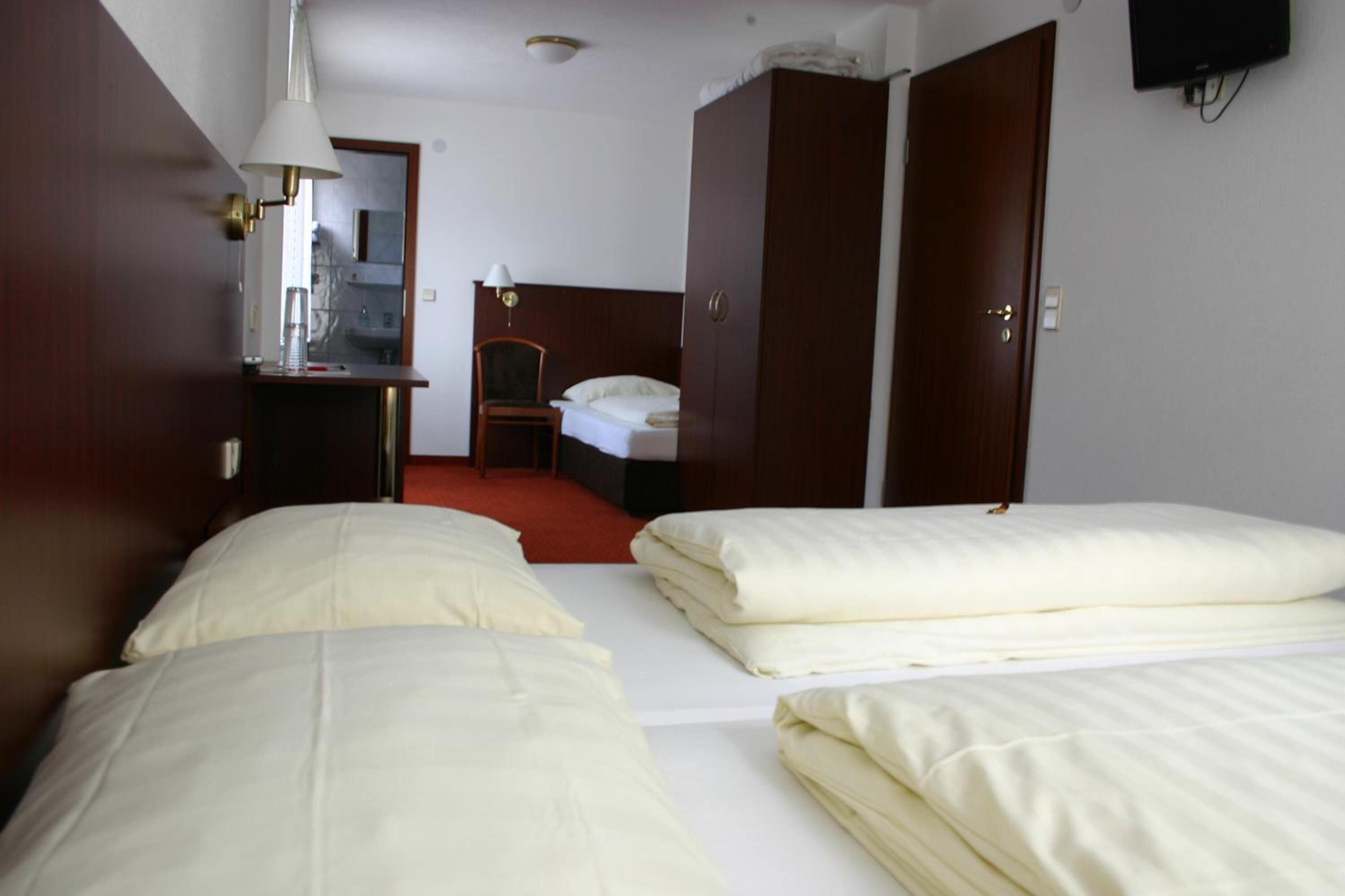 Une chambre d’hôtel avec deux lits, un bureau avec une lampe, un miroir et une armoire.