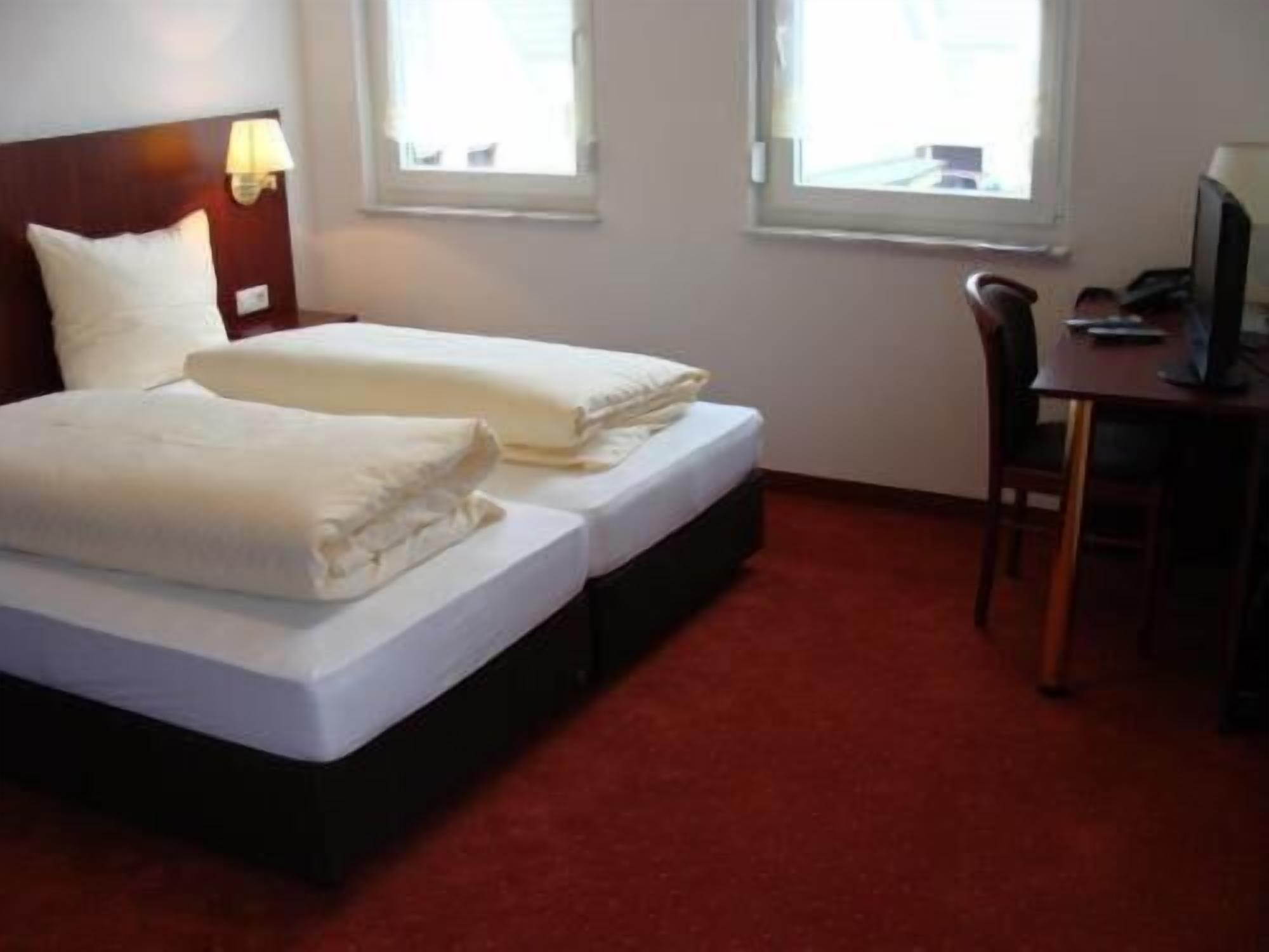 A hotel room with two beds, a desk, and a chair.