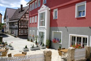 A traditional European street with a red and white building labeled "GASTHAUS" and "TRAUBE". - GasthausTraube (Dettingen an der Erms)