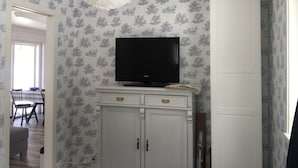 A room with a television on a cabinet, a dining area with chairs and a table, and a door. - ♥ Seaside cottage ♥ Boat fishing snowmobile running (Luleå Ö)