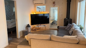 A cozy living room with a sofa, a flat-screen TV, a fireplace, and a door leading to a bedroom. - ♥ Seaside cottage ♥ Boat fishing snowmobile running (Luleå Ö)