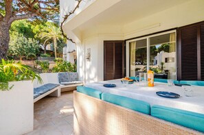 Enjoy al fresco dining in a serene outdoor space with a long table and comfortable seating.