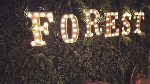 A restaurant interior with a wall of green foliage and illuminated letters spelling "FOREST". - Galtres Lodge Hotel (York)