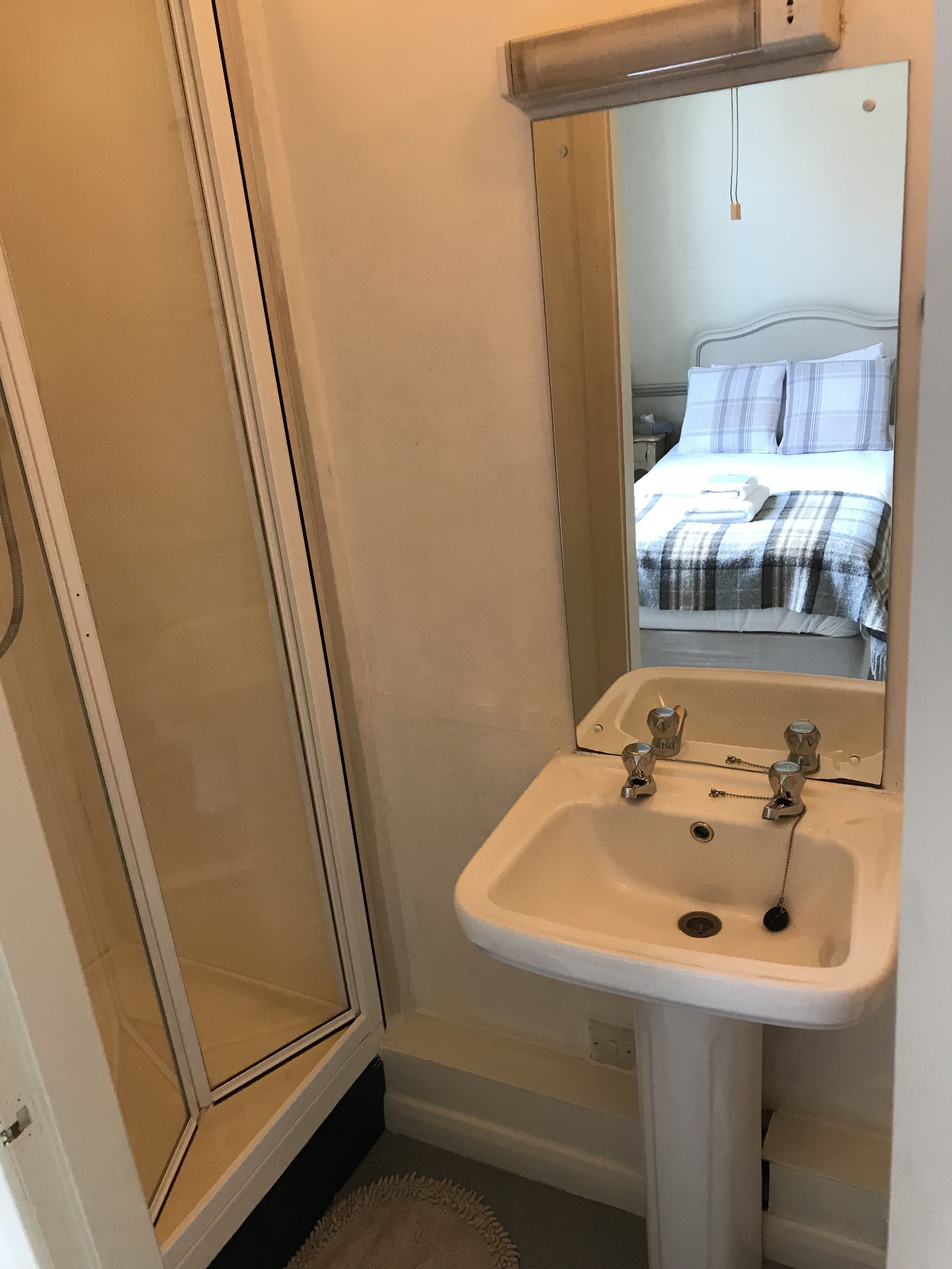 A bathroom with a white sink, a mirror, and a shower enclosure.