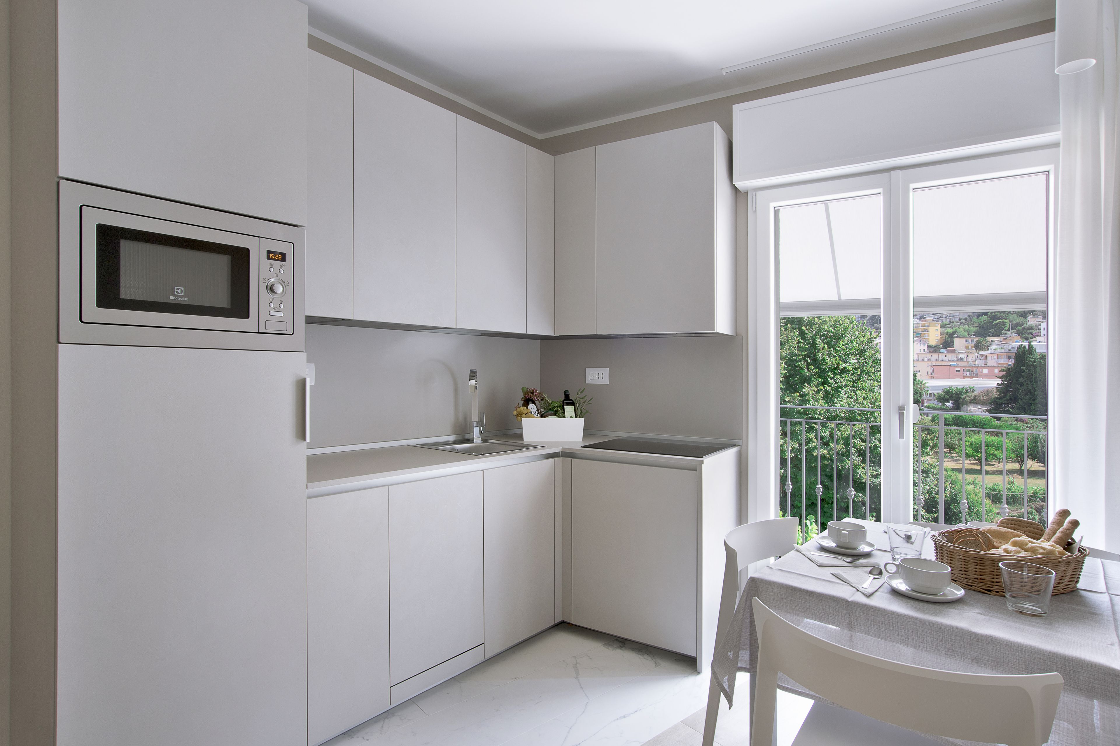 A modern kitchen with white cabinets, a built-in microwave, and a dining area with a table set for two.