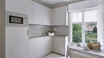 A modern kitchen with white cabinets, a built-in microwave, and a dining area with a table set for two.