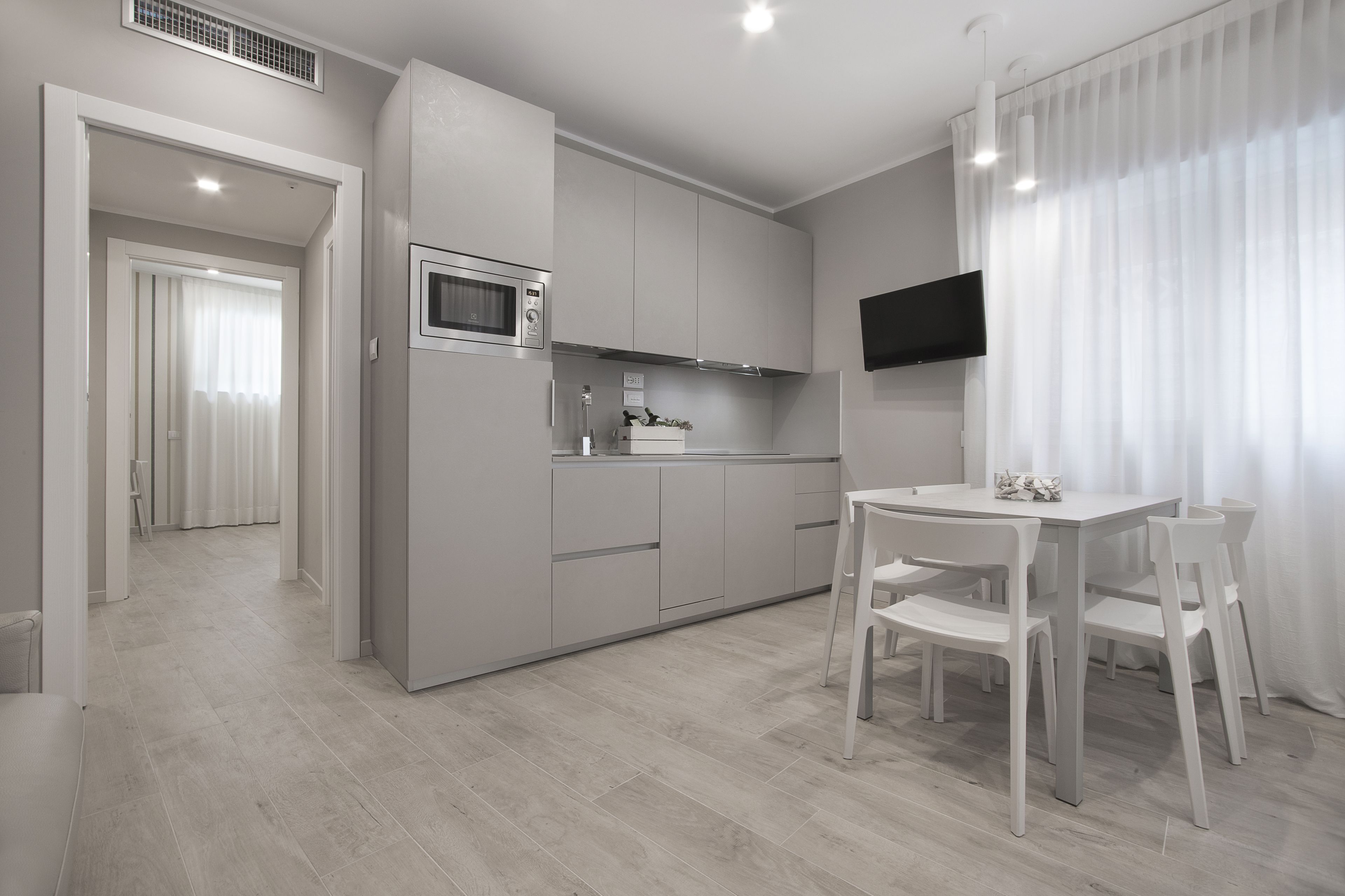 A modern kitchen with white cabinets, a microwave, and a dining area with a table and chairs.