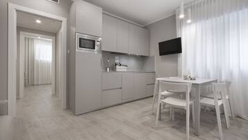 A modern kitchen with white cabinets, a microwave, and a dining area with a table and chairs.