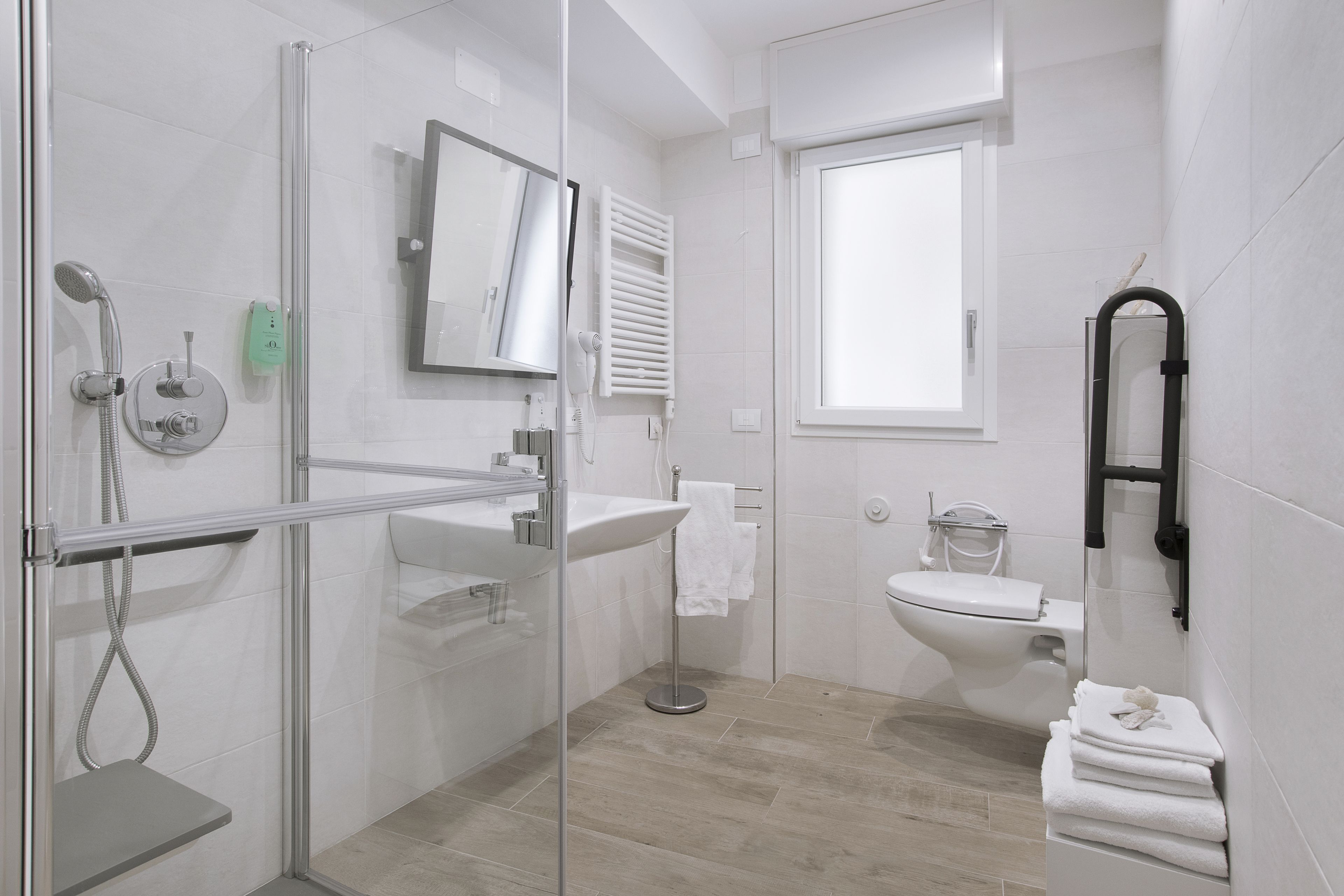 A modern bathroom with a glass-enclosed shower, a white sink, and a toilet.