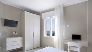 Une chambre à coucher avec un lit, un bureau avec un ordinateur portable, une télévision et une armoire.