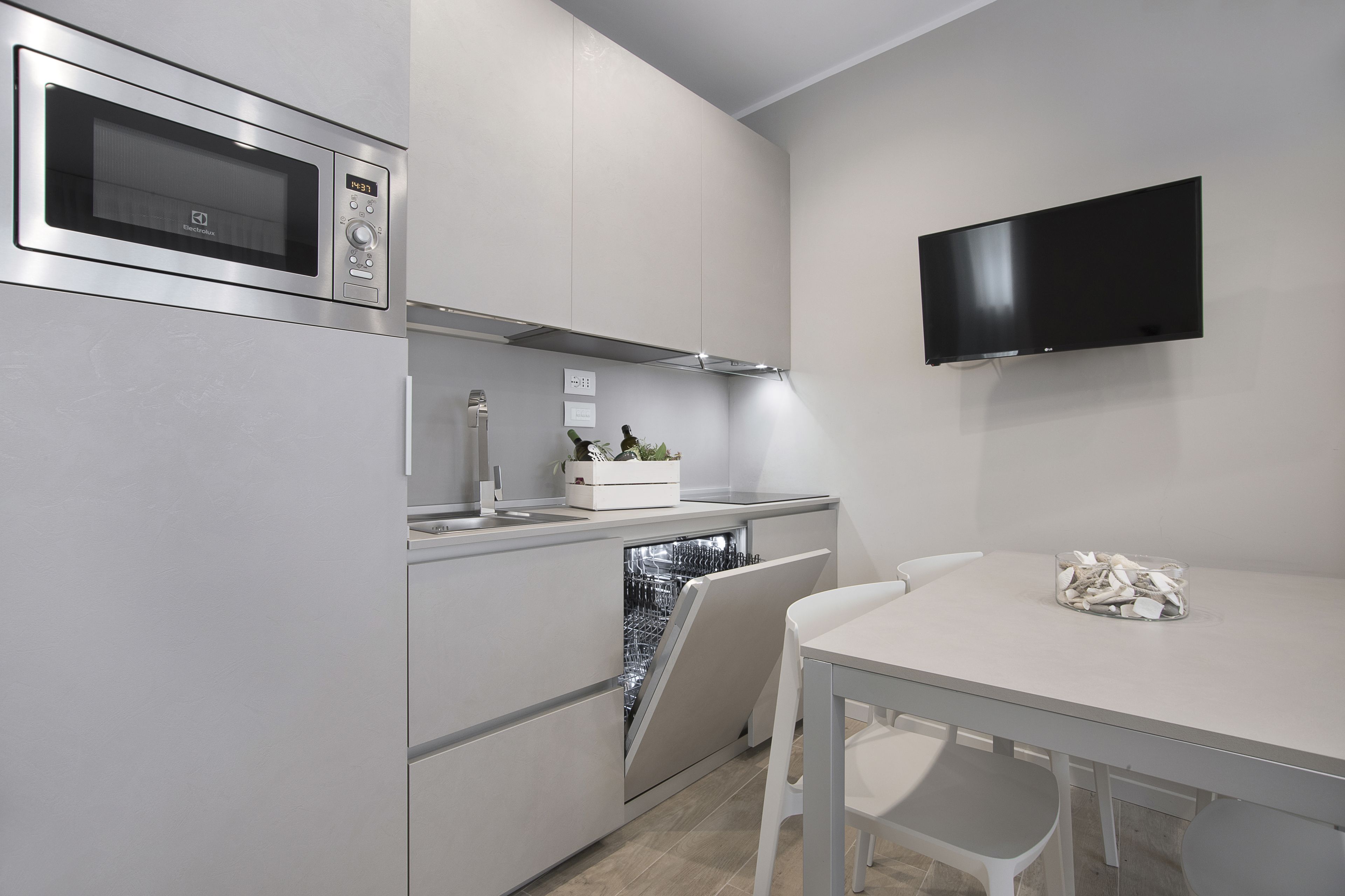 Eine moderne Küche mit eingebauter Mikrowelle, Geschirrspüler und einem flachbildfernseher an der Wand.