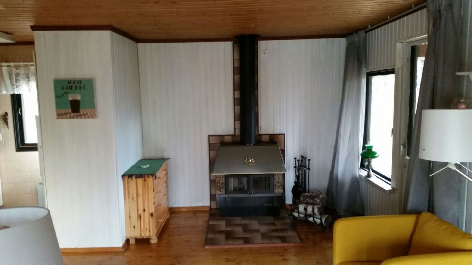 A cozy living room with a fireplace, wooden furniture, and a yellow armchair.