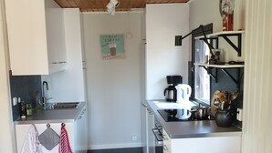 Une cuisine de taille réduite avec des meubles blancs, un plan de travail noir, une machine à café et une bouilloire.