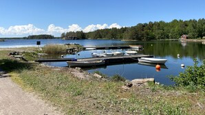 Une jetée au bord du lac, avec des bateaux amarrés, une maison rouge et une rive bordée d’arbres.