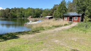 Un chalet au bord du lac, doté d’un quai, entouré d’arbres et offrant une vue sur un ciel dégagé.
