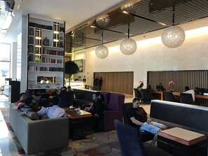 A modern lobby with seating areas, a bookshelf, and a reception desk.