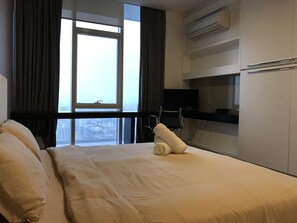 A hotel room with a bed, a TV, and a city view.
