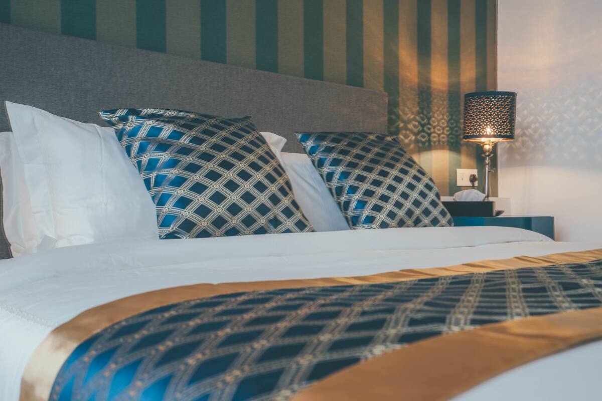A neatly made bed with patterned pillows and a decorative headboard.