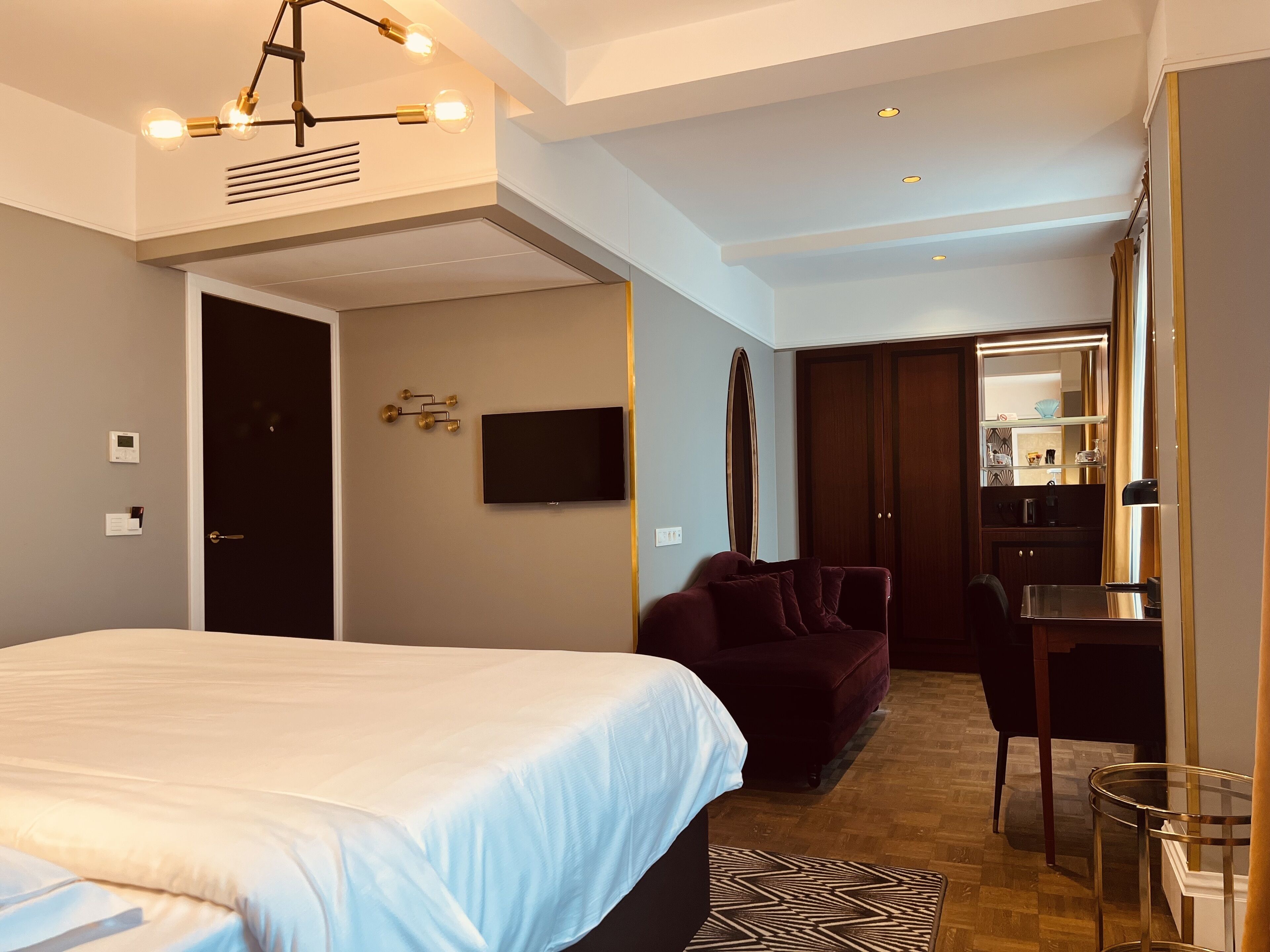 Una habitación de hotel moderna con una cama grande, un escritorio, una silla y un televisor.