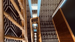 Een wenteltrap met een geometrisch vloerkleed en houten leuningen.