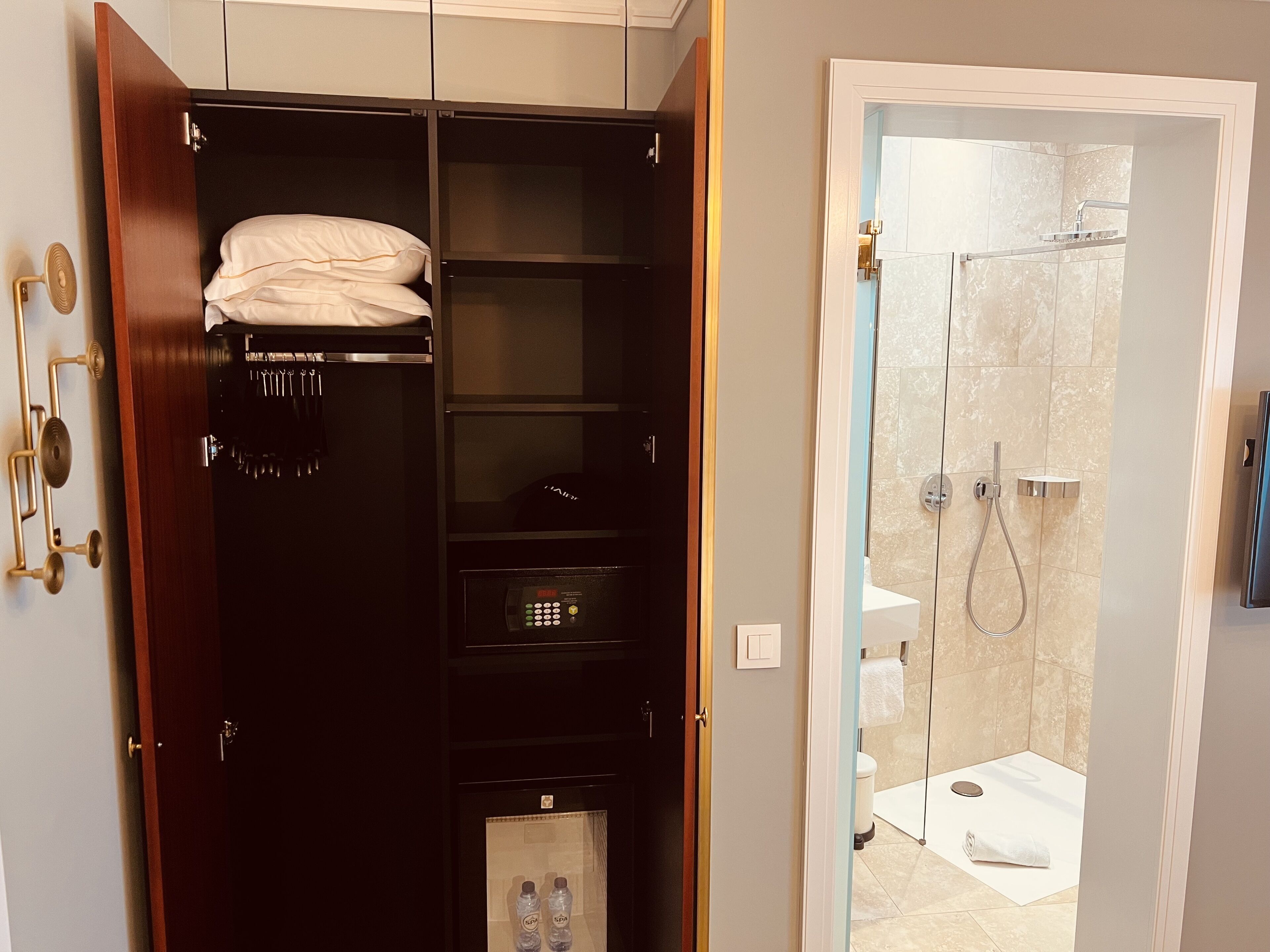 A walk-in closet with a dark wood finish, a built-in heater, and a shelf with folded towels.