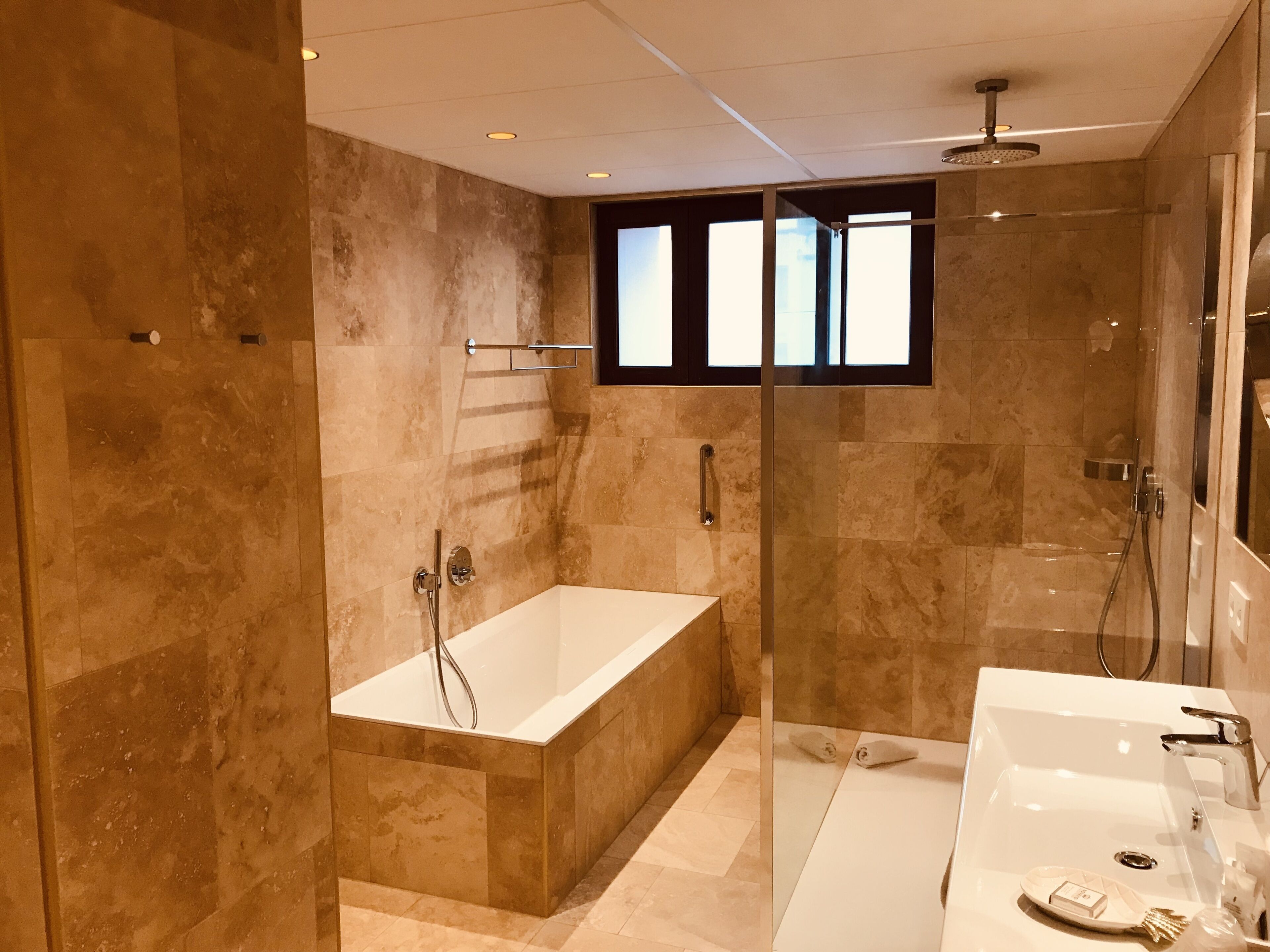 Un baño moderno con ducha de vidrio, una bañera independiente y un tocador con lavabo.