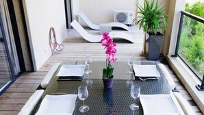 Un coin repas avec une table dressée pour six personnes, entourée de chaises en osier.