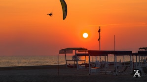 A beach scene with parasailing activity during sunset. - Camping Viareggio (Viareggio)