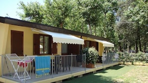 A small, single-story building with a covered porch and a fenced outdoor seating area. - Camping Viareggio (Viareggio)